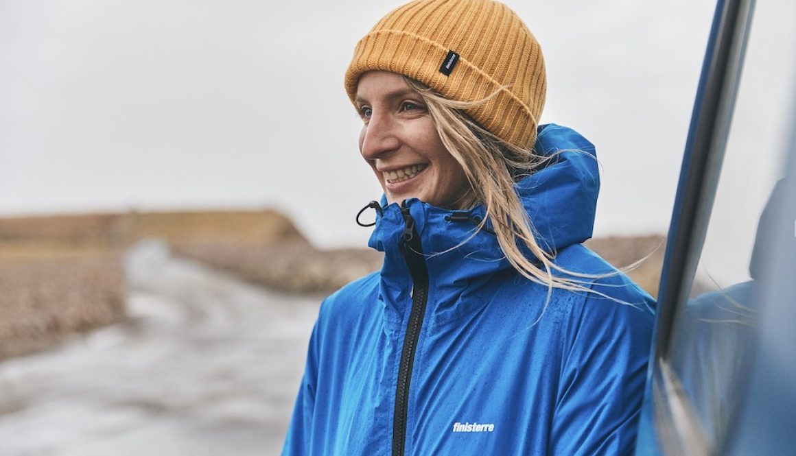 Dr Easkey Britton on board a boat at sea on the coast of Ireland wearing a yellow Finisterre hat and blue finisterre raincoat