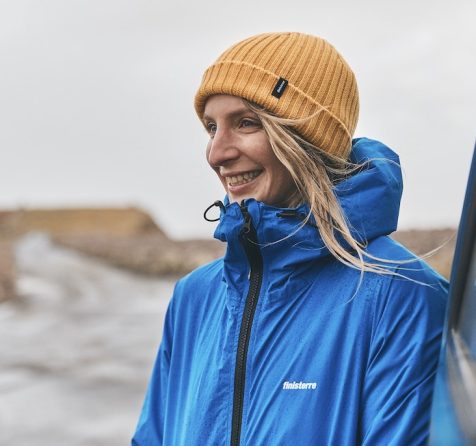 Dr Easkey Britton on board a boat at sea on the coast of Ireland wearing a yellow Finisterre hat and blue finisterre raincoat