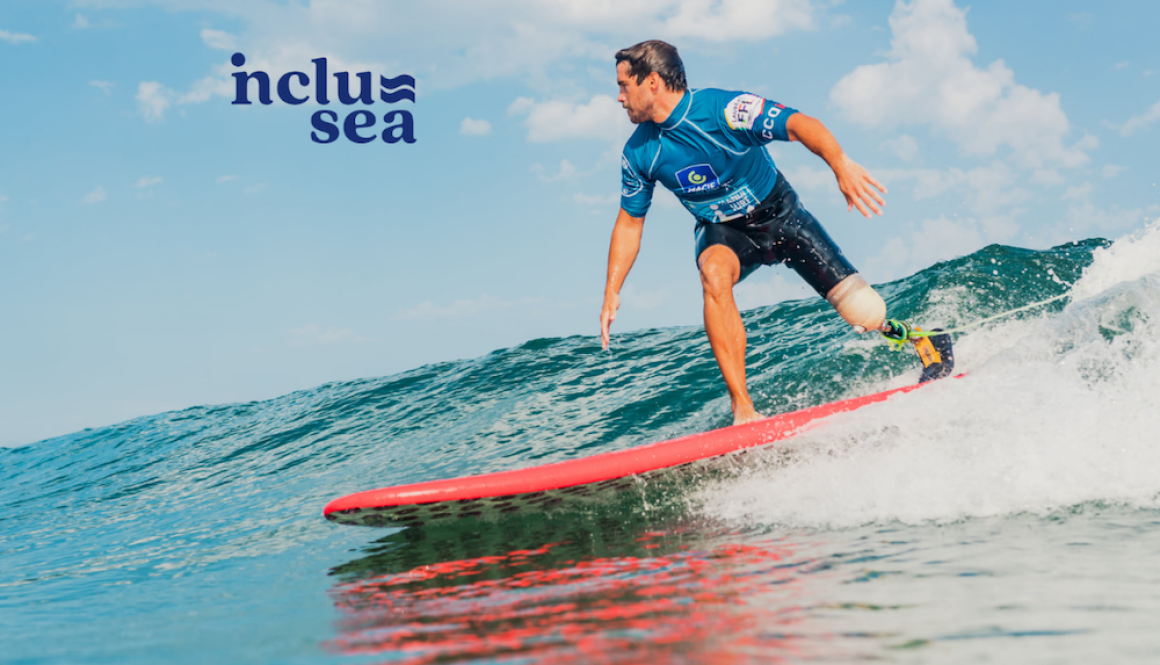 Inclusea adaptive surfing image of a man wearing a shortie wetsuit and blue rash vest with a prosthetic leg surfing an unbroken wave on a red surfboard.